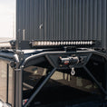 Load image into Gallery viewer, Roof rack with LED light bar on a vehicle, against a building background